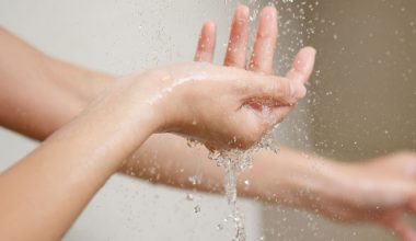 Manos de una mujer lavándose con agua tibia, representando el cuidado de la higiene íntima femenina