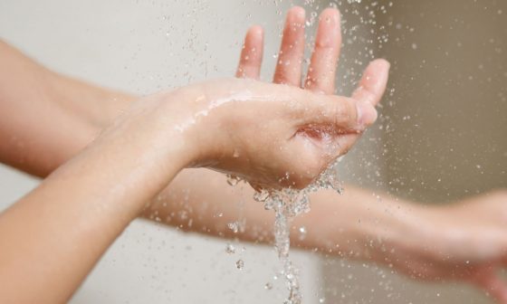 Manos de una mujer lavándose con agua tibia, representando el cuidado de la higiene íntima femenina